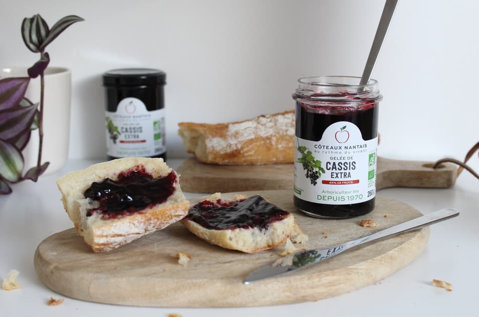 Blackcurrant jelly spread on bread, next to the jar