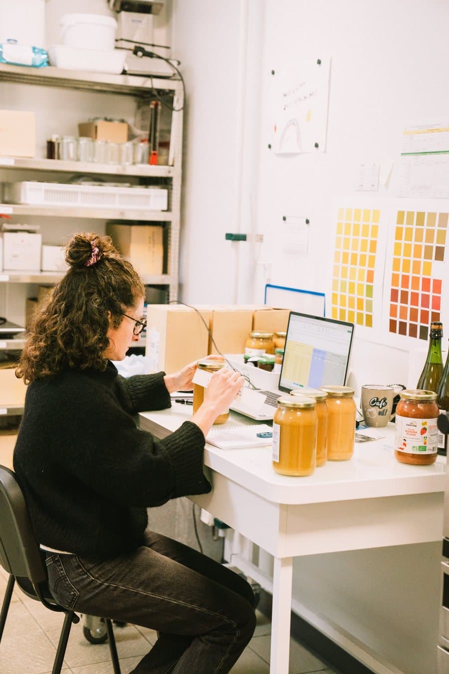 A laboratory team member records results on a computer, surrounded by jars of compote and colour charts